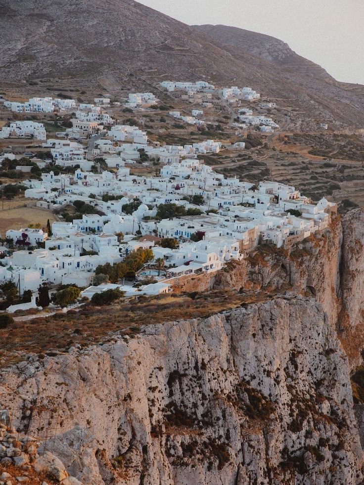 This may contain: an aerial view of a village on the side of a cliff with mountains in the background
