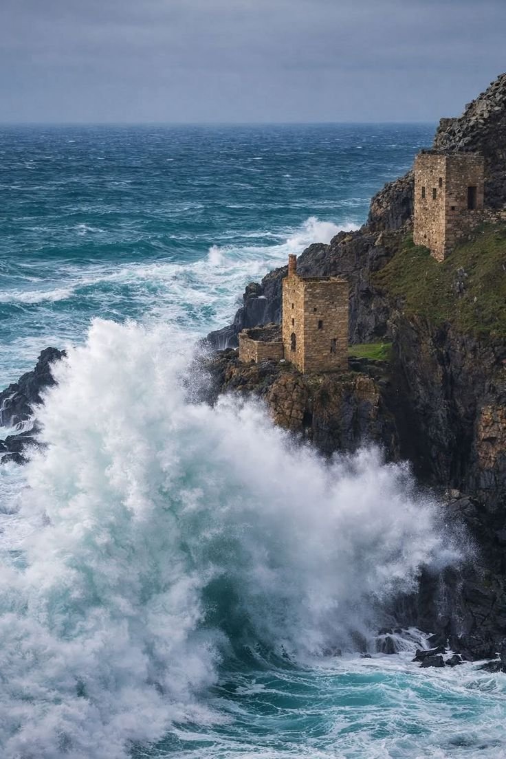 This may contain: waves crashing against the rocky shore near an old stone building in the middle of the ocean