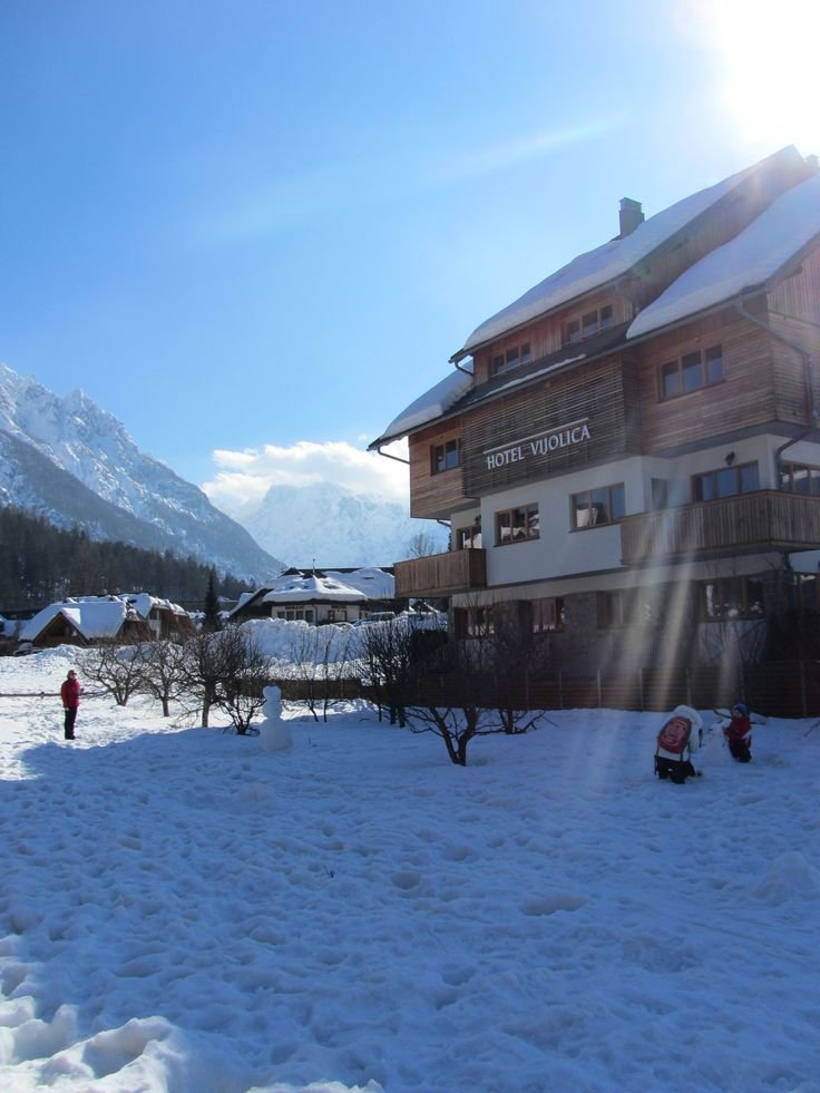 This may contain: the sun shines brightly in front of a snow - covered building with mountains in the background