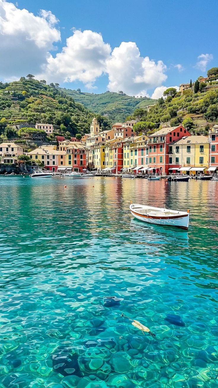 This may contain: a boat floating on top of a body of water next to a hillside covered with houses