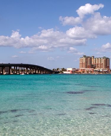 This may contain: the water is crystal blue and there are many buildings in the background with a bridge crossing over it