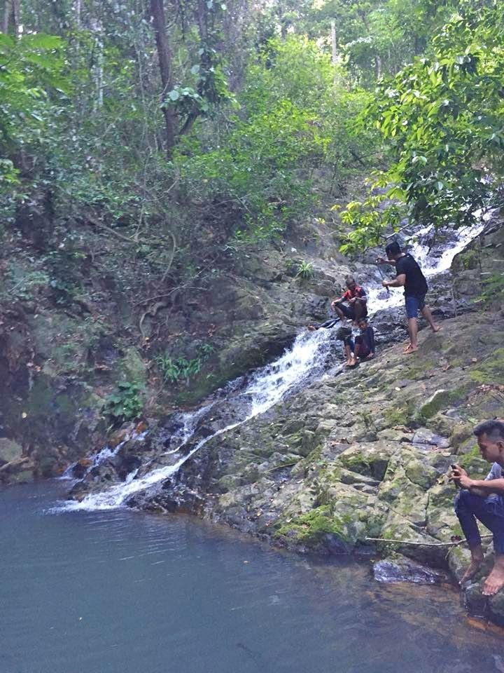 This may contain: three people standing on the side of a waterfall