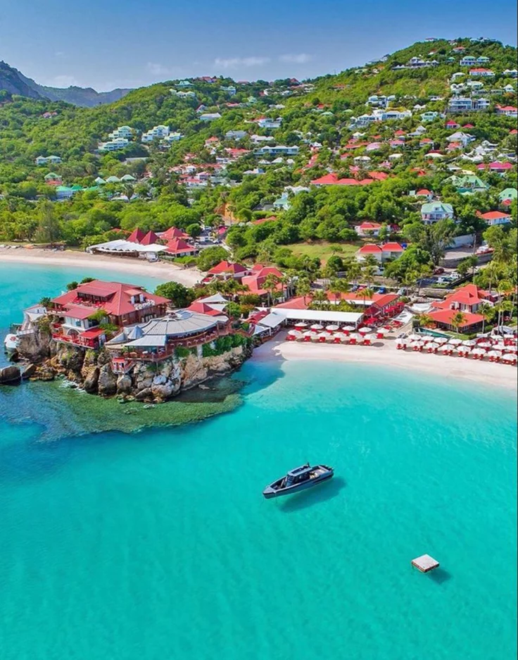 This may contain: an aerial view of a beach with boats in the water and houses on land next to it