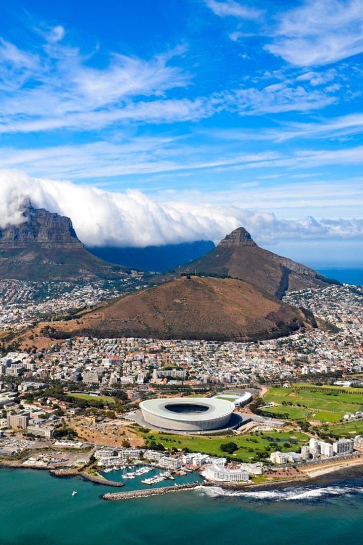This may contain: an aerial view of cape town with table mountain in the background and clouds over it