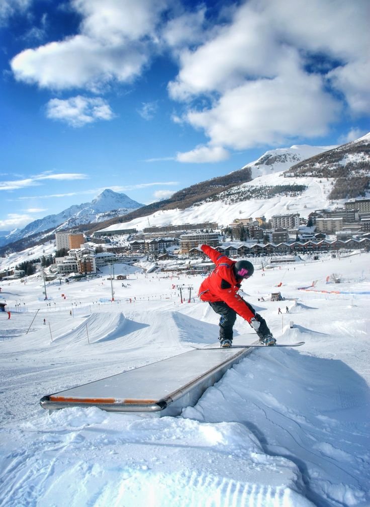 This may contain: a man riding a snowboard down the side of a ramp