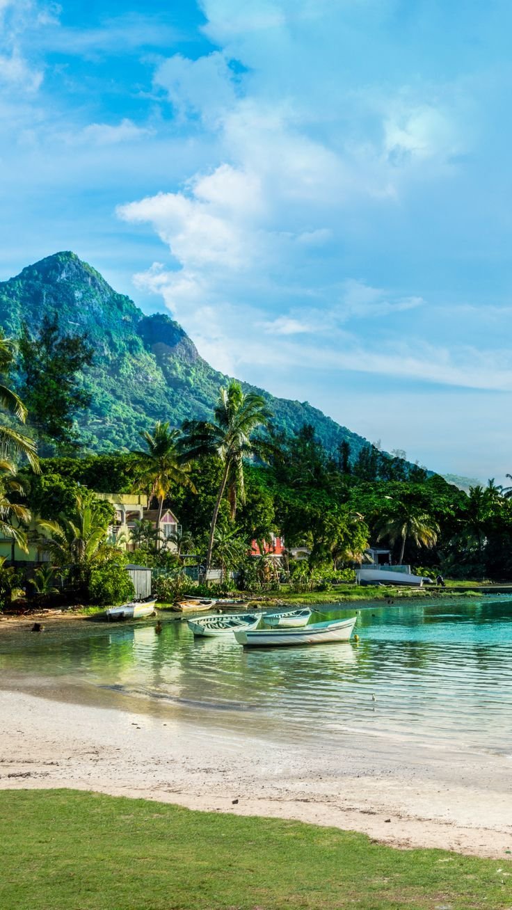 This may contain: there are boats that are sitting in the water on the beach near some trees and mountains