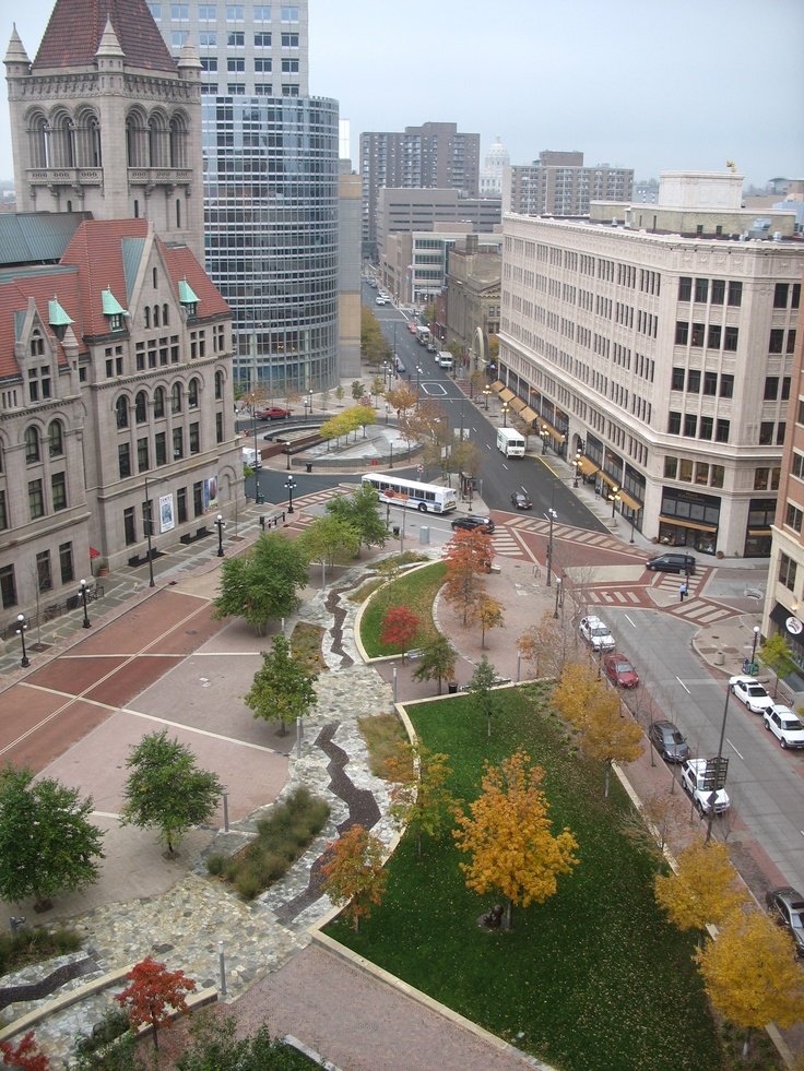 This may contain: an aerial view of a city street with tall buildings and trees in the foreground
