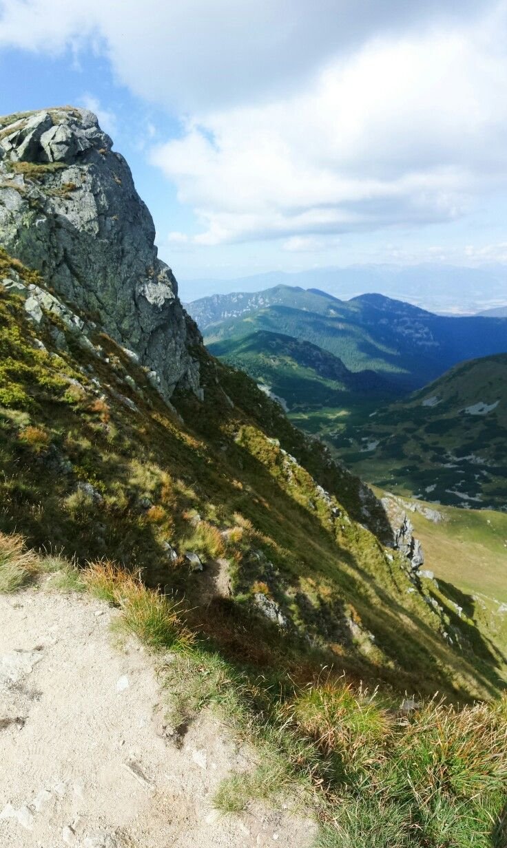 This may contain: a man is sitting on top of a mountain looking down at the valley and mountains