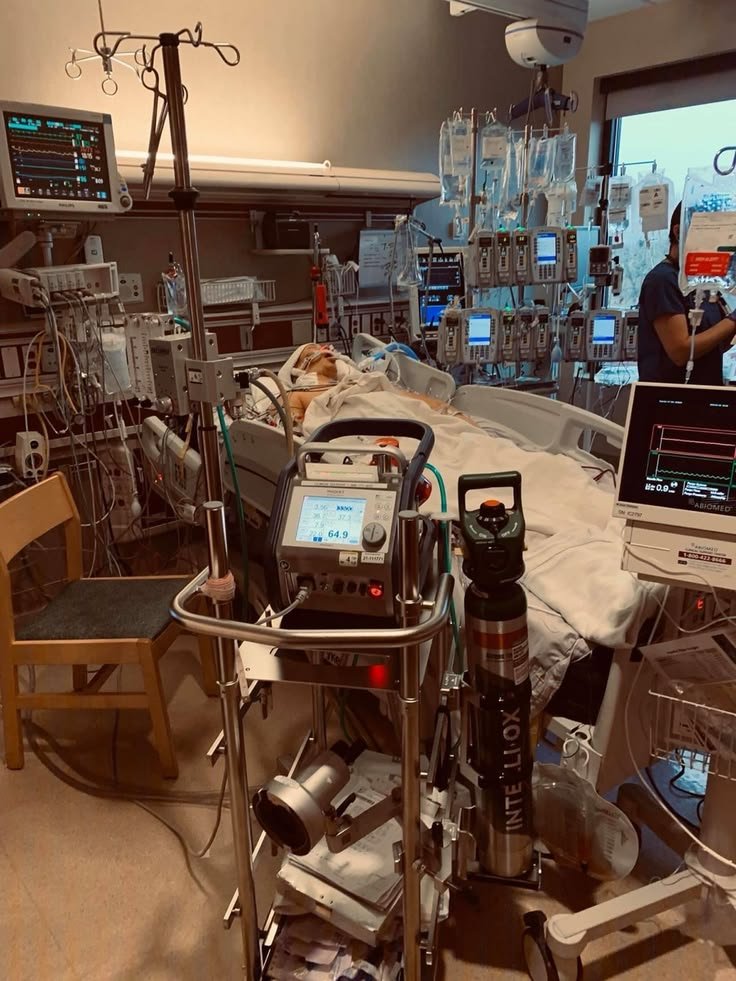 This may contain: a hospital room filled with medical equipment and lots of monitors on each side of the room