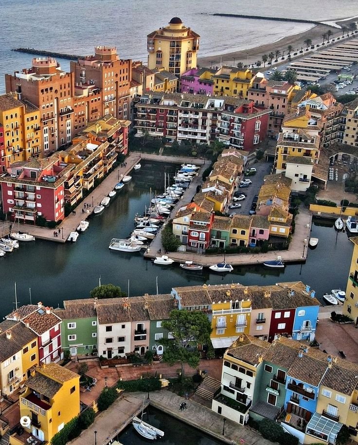 This may contain: an aerial view of boats docked in the water next to colorful buildings and beachfronts