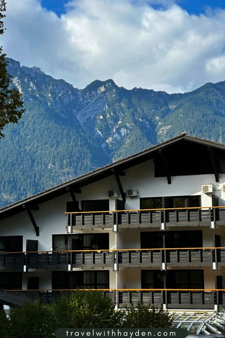 This may contain: an apartment building with mountains in the background