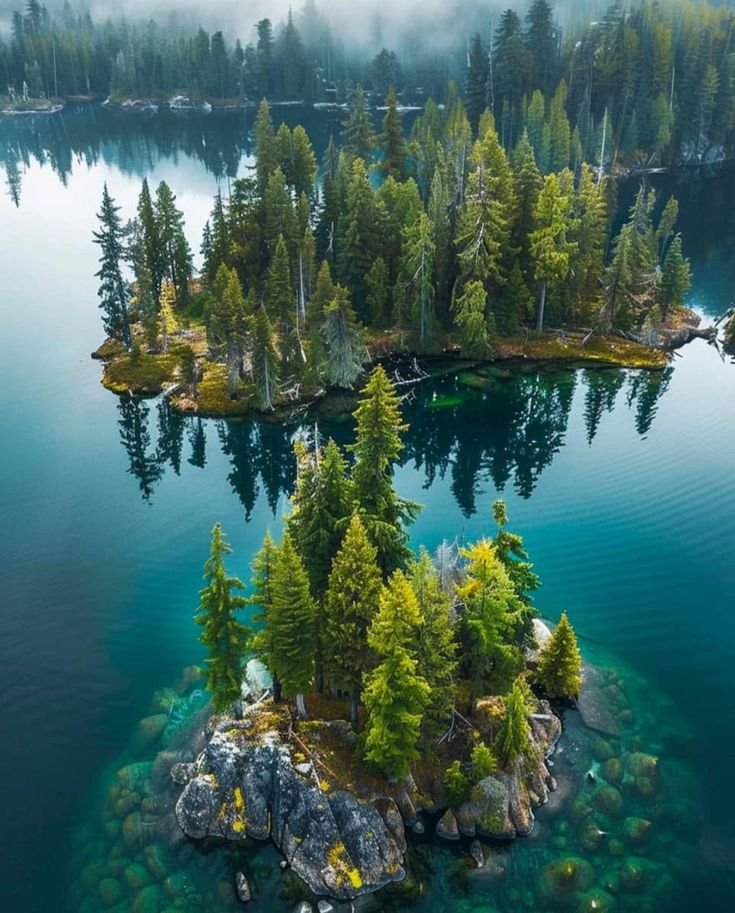 This may contain: an island in the middle of a lake surrounded by trees