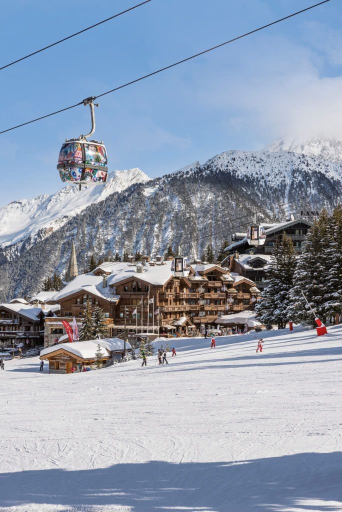 This may contain: the ski lift is carrying skiers down the snowy mountain side area in front of houses