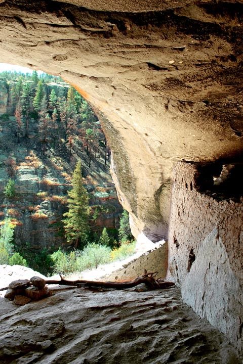 This may contain: an open window in the side of a cliff with trees and mountains in the background