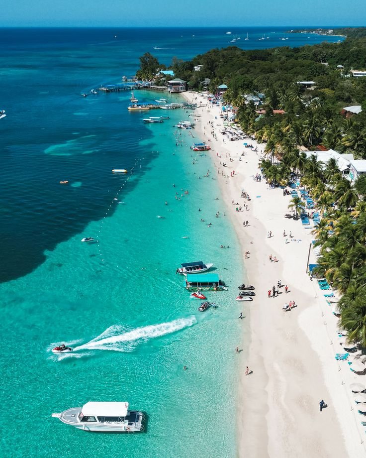 This may contain: an aerial view of a beach with boats and people