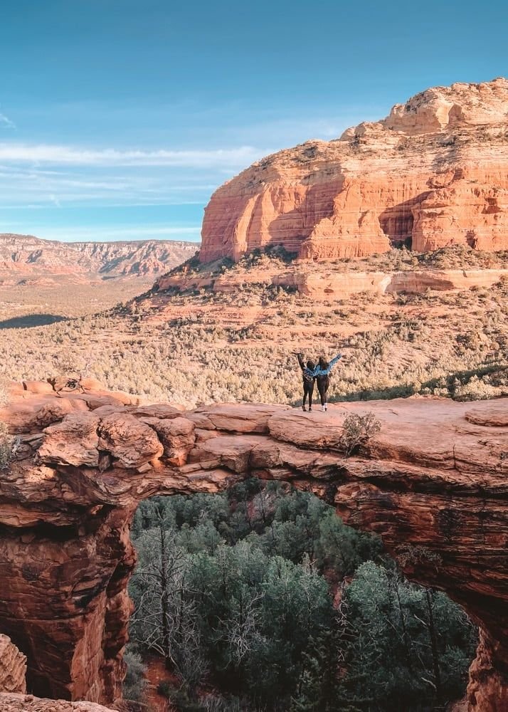 This may contain: two people standing on the edge of a cliff