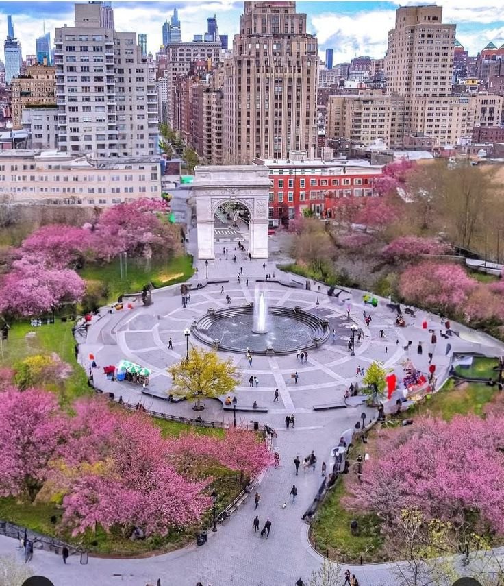 This may contain: an aerial view of a park with pink flowers and people walking around it in the city