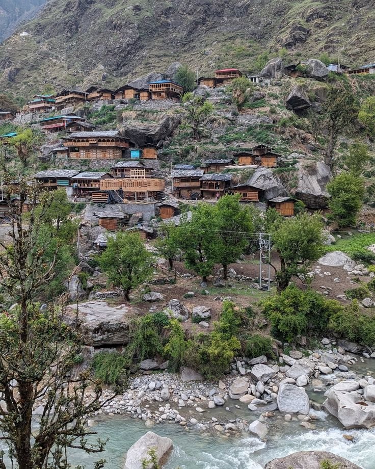 This may contain: a village on the side of a mountain next to a river