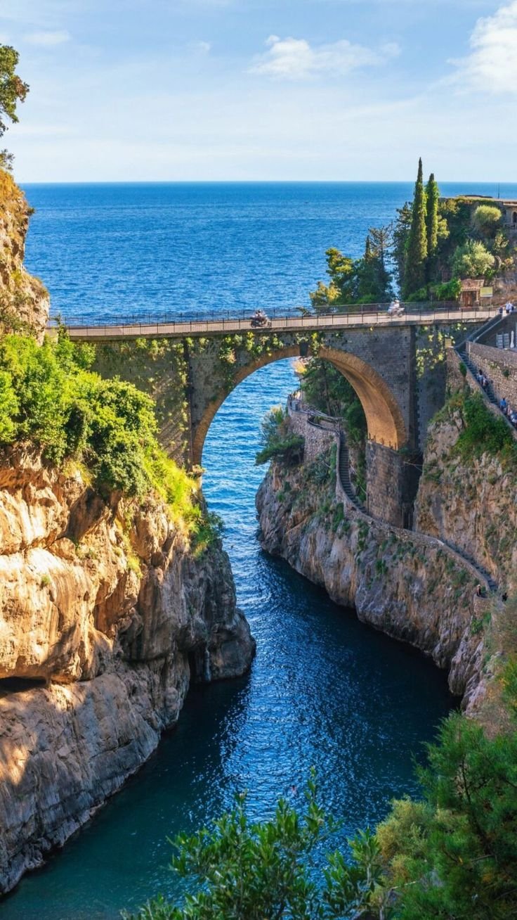 This may contain: an old bridge over a river next to the ocean