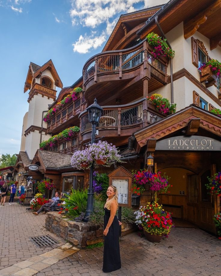 This may contain: a woman standing in front of a building with lots of flowers on the balconies