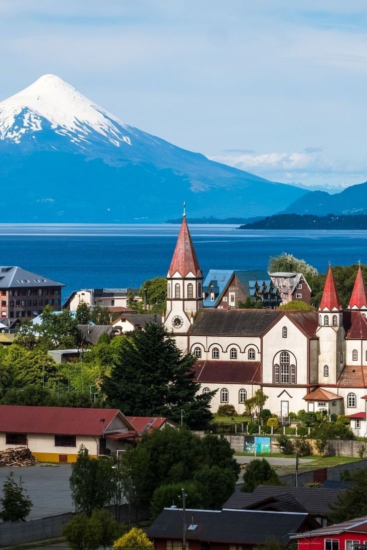 This may contain: a city with mountains in the background and snow capped mountain in the distance behind it