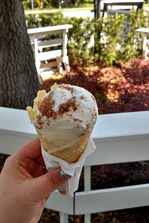 This may contain: a person holding up an ice cream cone with cinnamon on it in front of a table