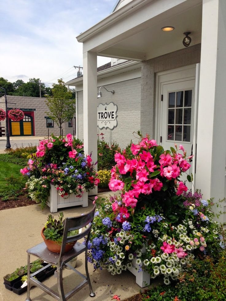 This may contain: some flowers are in pots on the side of a building and there is a sign that says trove