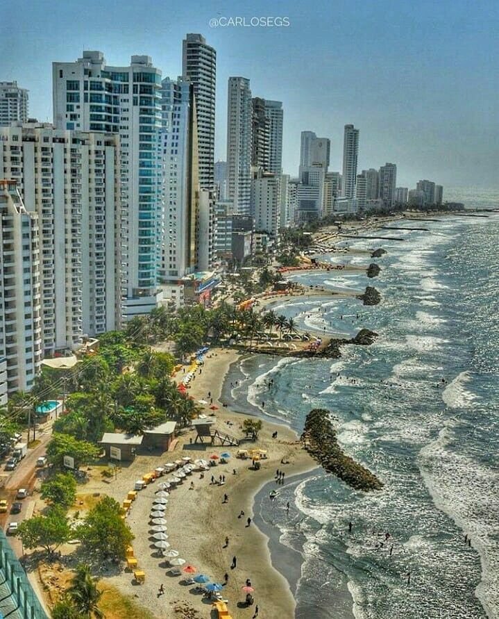 This may contain: the beach is lined with tall buildings and people