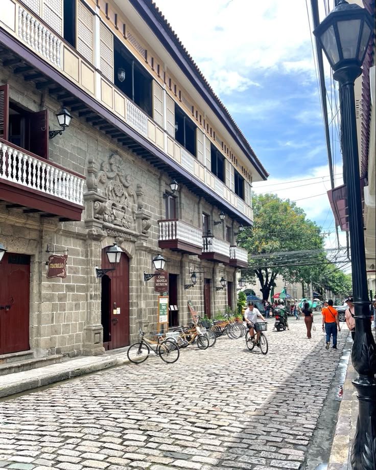 This may contain: people walking and riding bikes on a cobblestone street