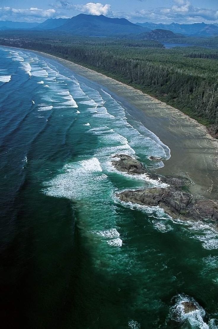 This may contain: an aerial view of the ocean and beach with waves crashing on it's shore