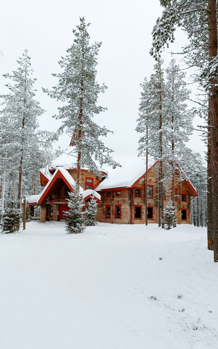 This may contain: a large house surrounded by trees covered in snow