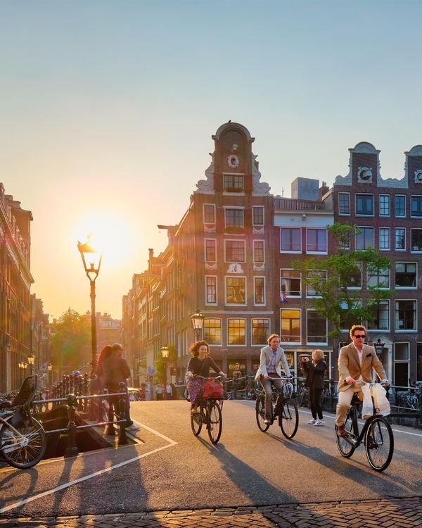 This may contain: people are riding bicycles down the street at sunset