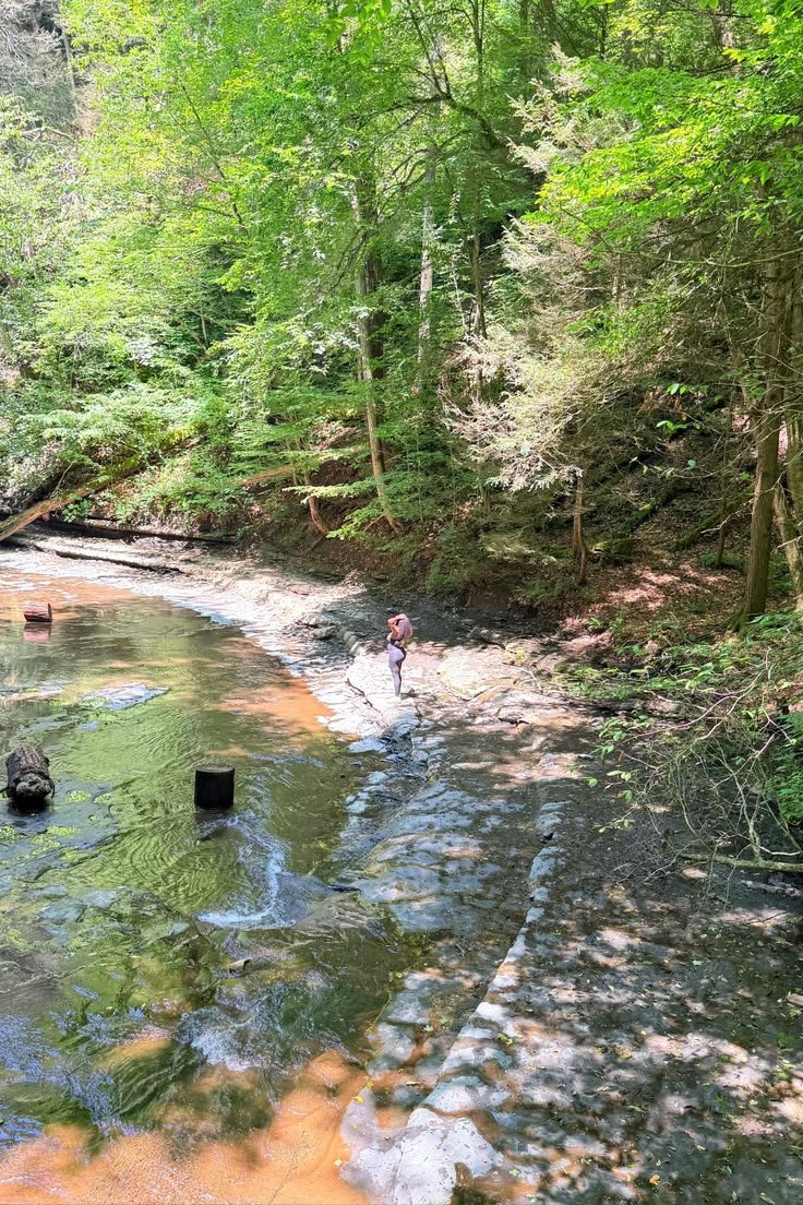 This may contain: a man wading through a river surrounded by trees