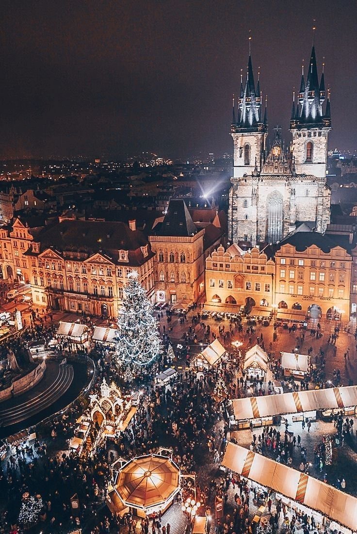 This may contain: an aerial view of the christmas market in prague, germany at night with lights on