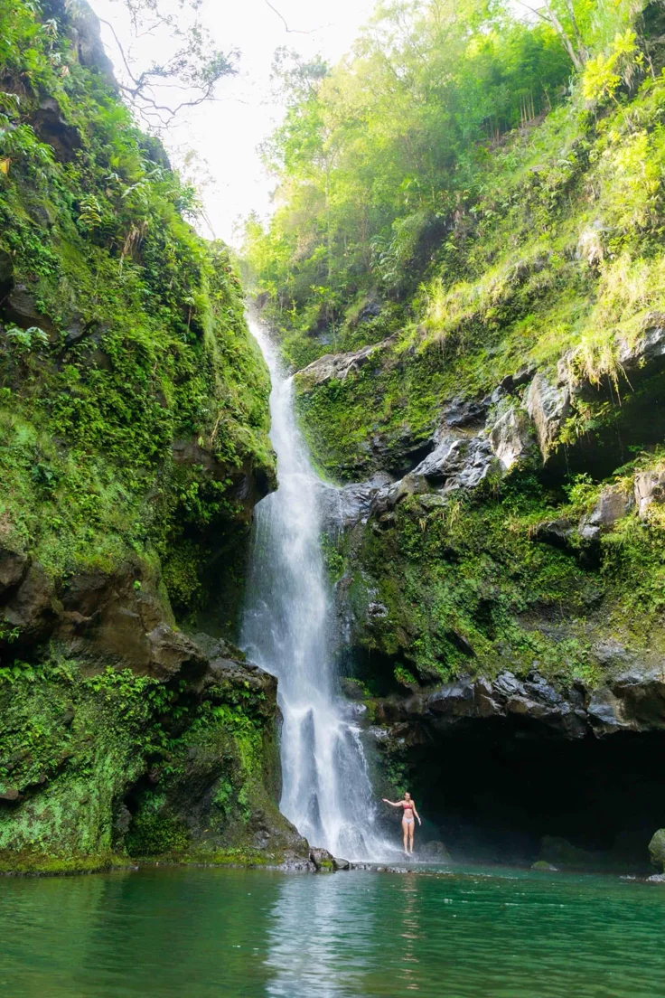 This may contain: a person standing in the water near a waterfall