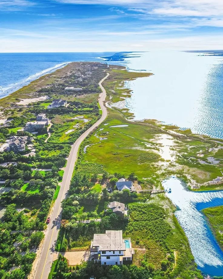 This may contain: an aerial view of the beach and ocean in front of a house with lots of trees