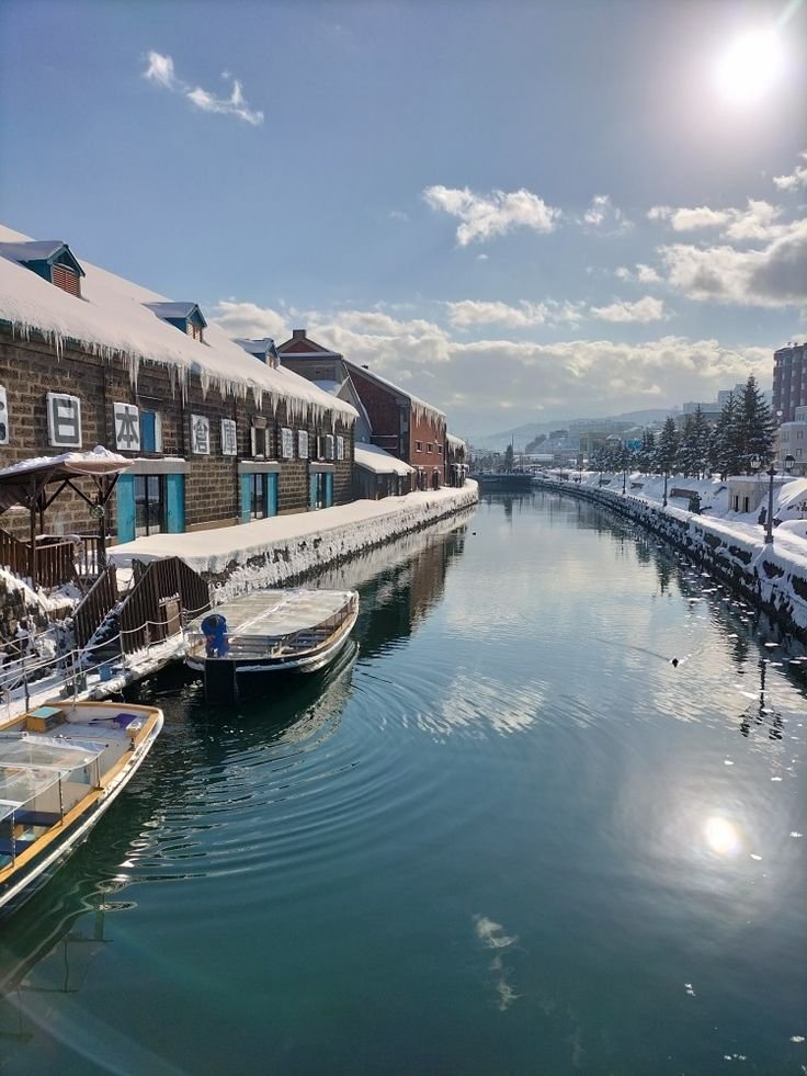 This may contain: several boats are docked in the water next to buildings and snow covered rooftops on either side
