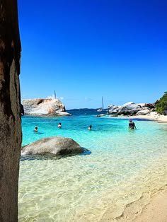 This may contain: people are swimming in the clear blue water on a sunny day at an island beach