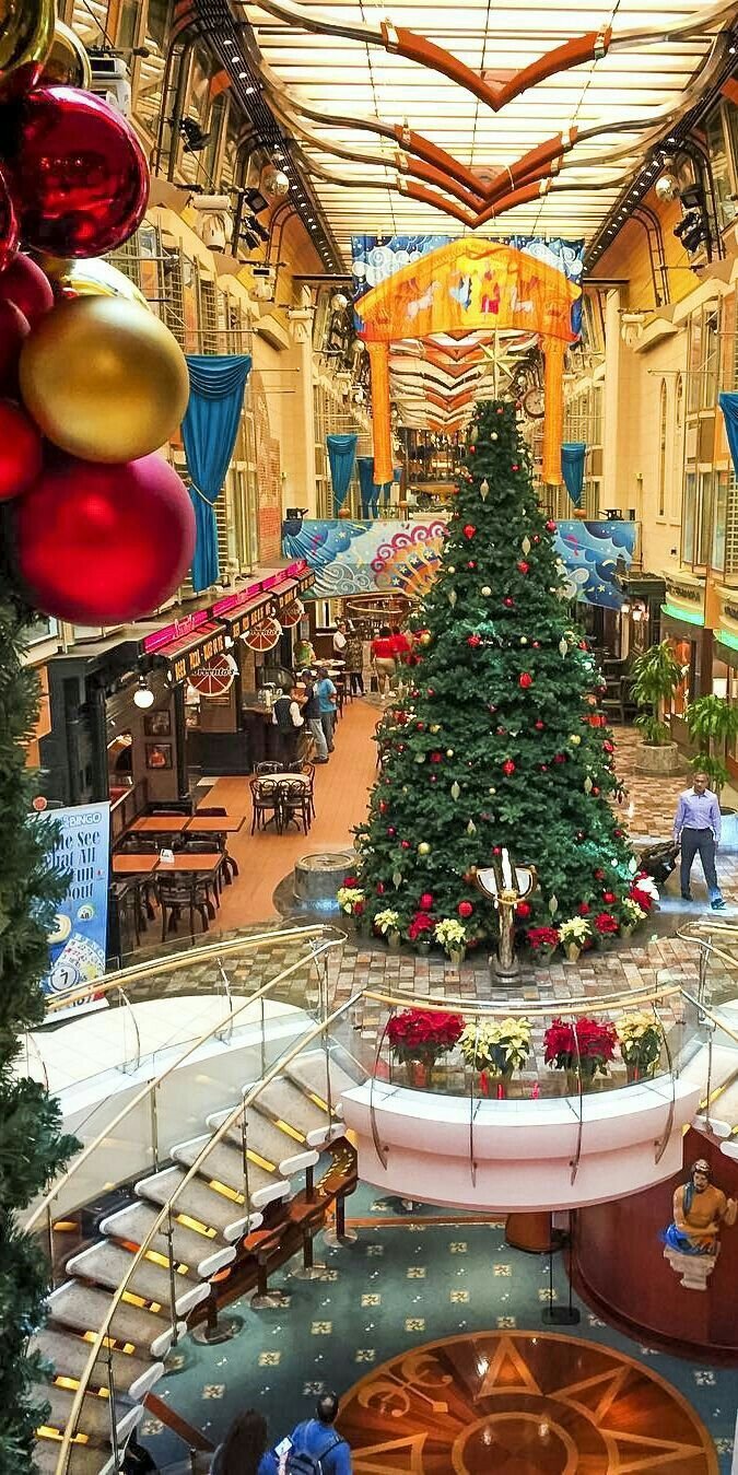 This may contain: a christmas tree in the middle of a mall with decorations on it's sides