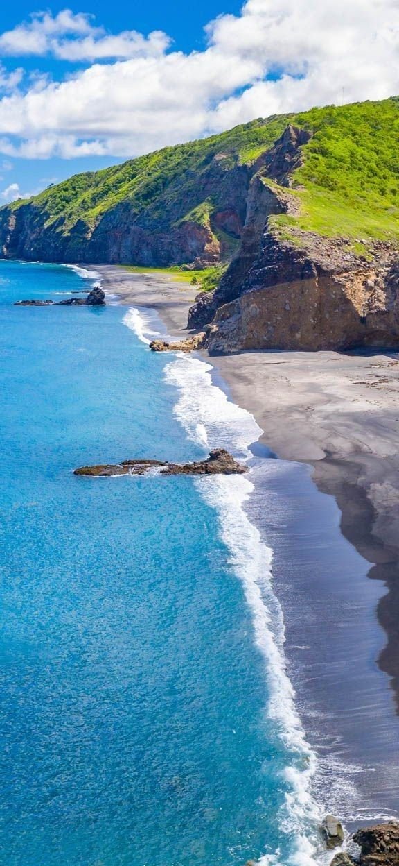 This may contain: the ocean is blue and clear with waves coming in from the shore, along with green hills