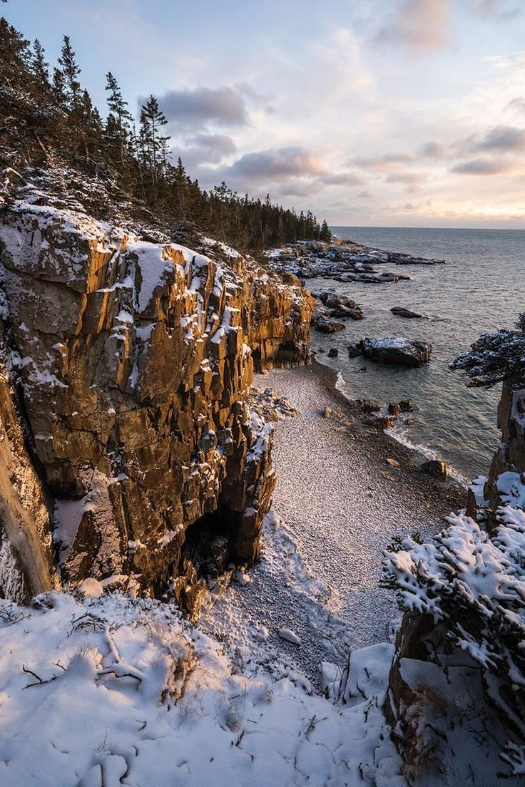 This may contain: a rocky cliff with snow on the ground