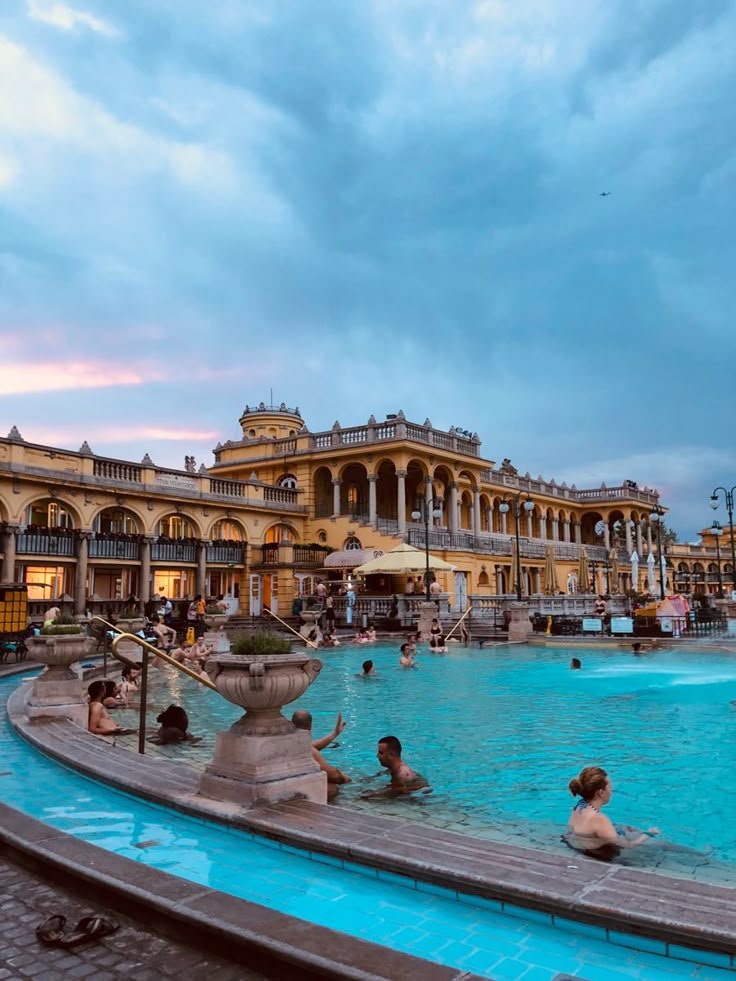 This may contain: people are swimming in an outdoor pool at dusk