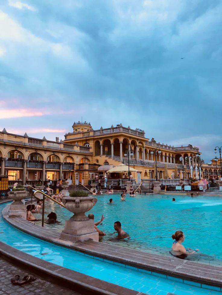 This may contain: people are swimming in an outdoor pool at dusk