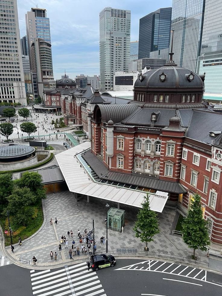This may contain: an aerial view of a city with tall buildings and people walking on the street in front of it