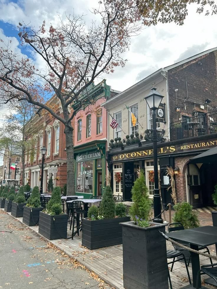 This may contain: a row of buildings with tables and chairs on the sidewalk