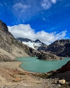 This may contain: a large body of water sitting in the middle of a rocky mountain range under a blue sky