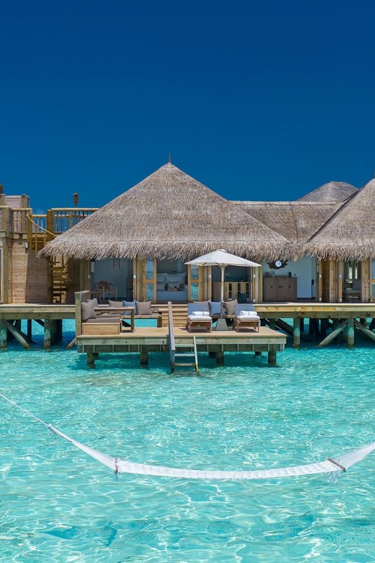 This may contain: the water is crystal blue and there are some huts on stilts in the background