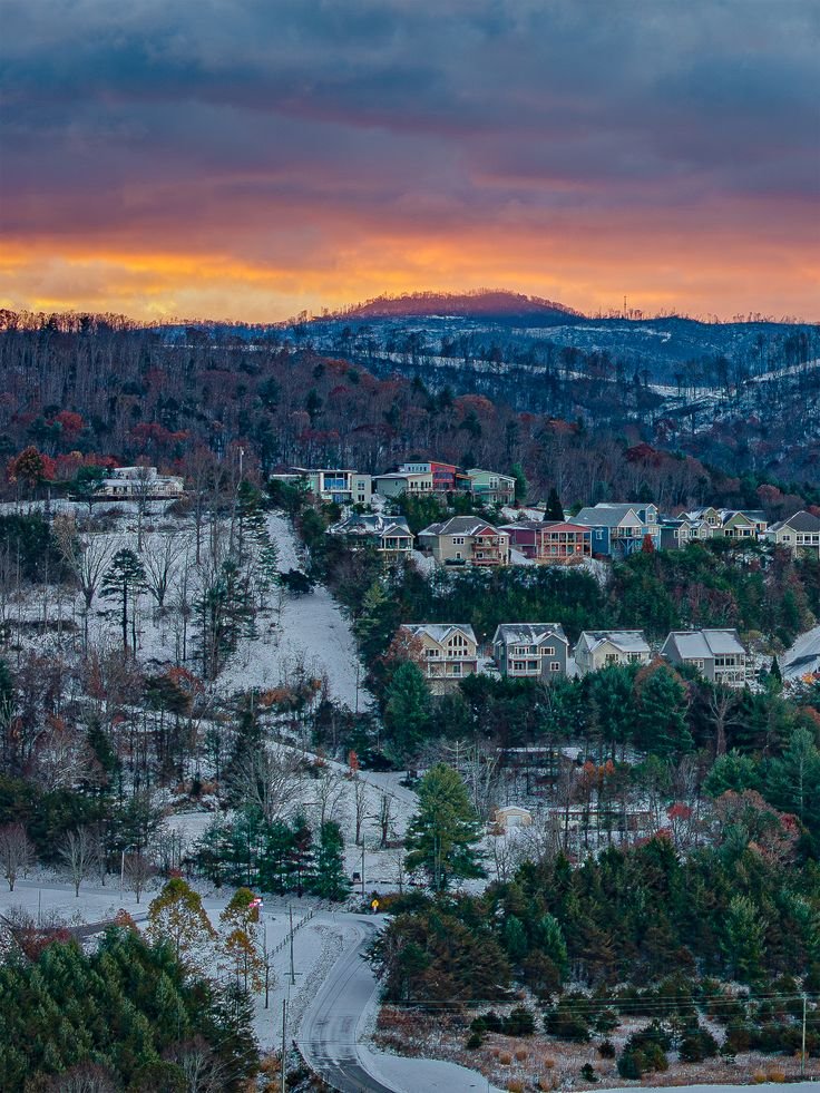 This may contain: the sun is setting over a city with trees and mountains in the background, as seen from an overlook point