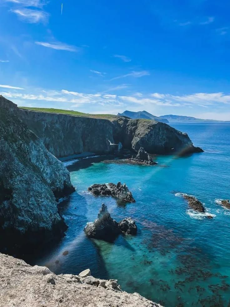 This may contain: the water is crystal blue and clear at this point in the ocean near some rocks