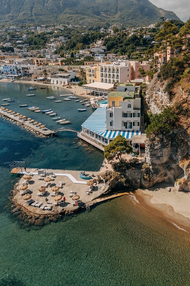 This may contain: an aerial view of a beach with boats in the water and buildings on the shore